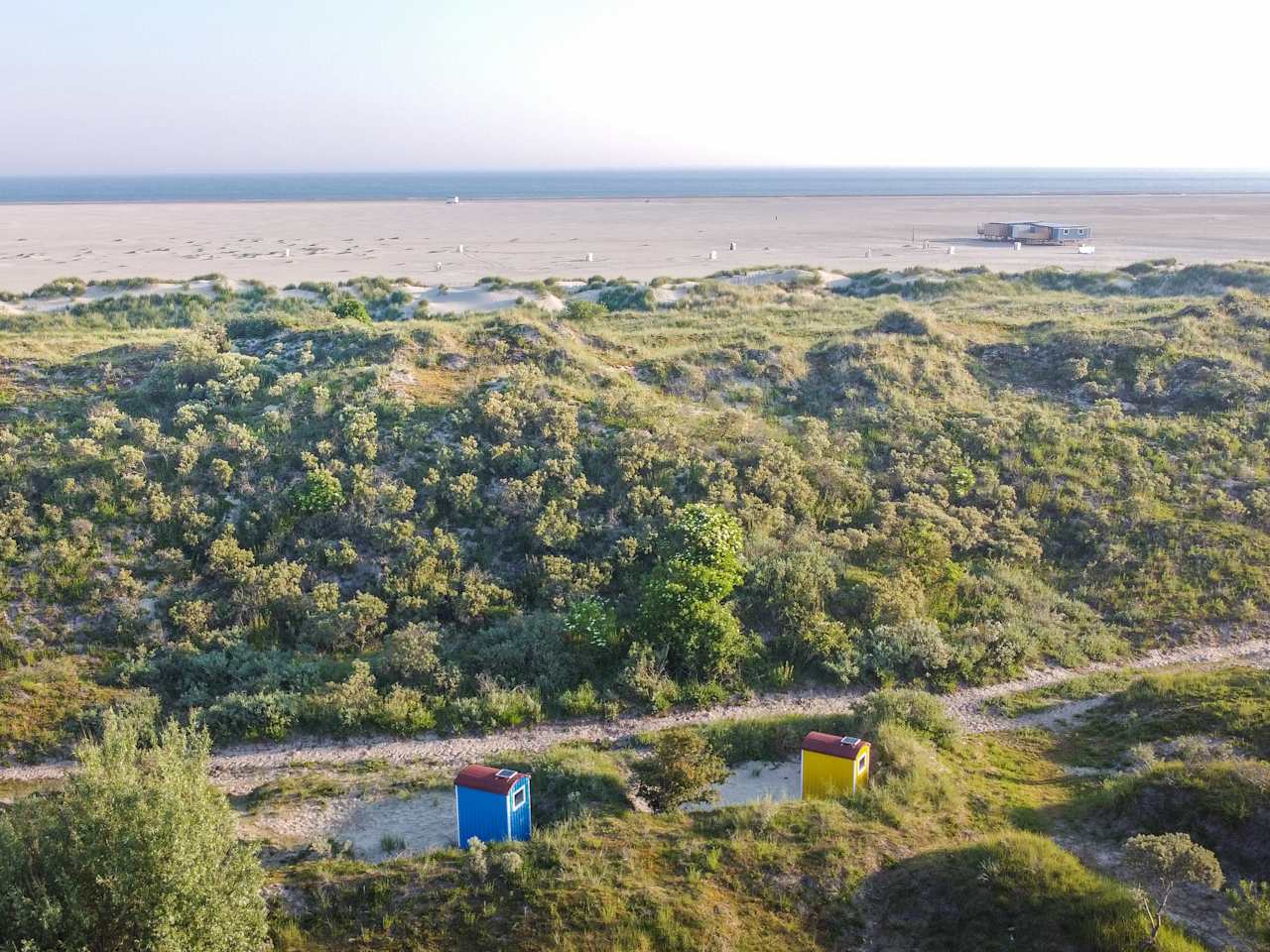 Blick auf einen Strand mit kleinen bunten Häuschen in den Dünen